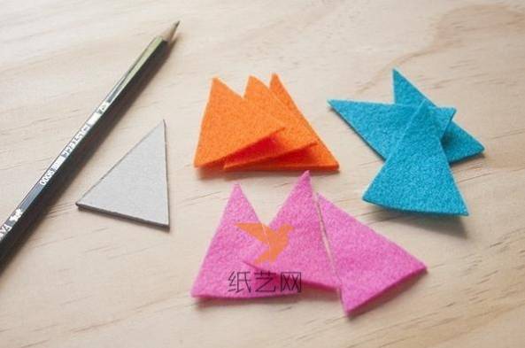 先用白纸剪出大小合适的三角形，然后比照这个三角形剪出三种颜色的不织布三角形